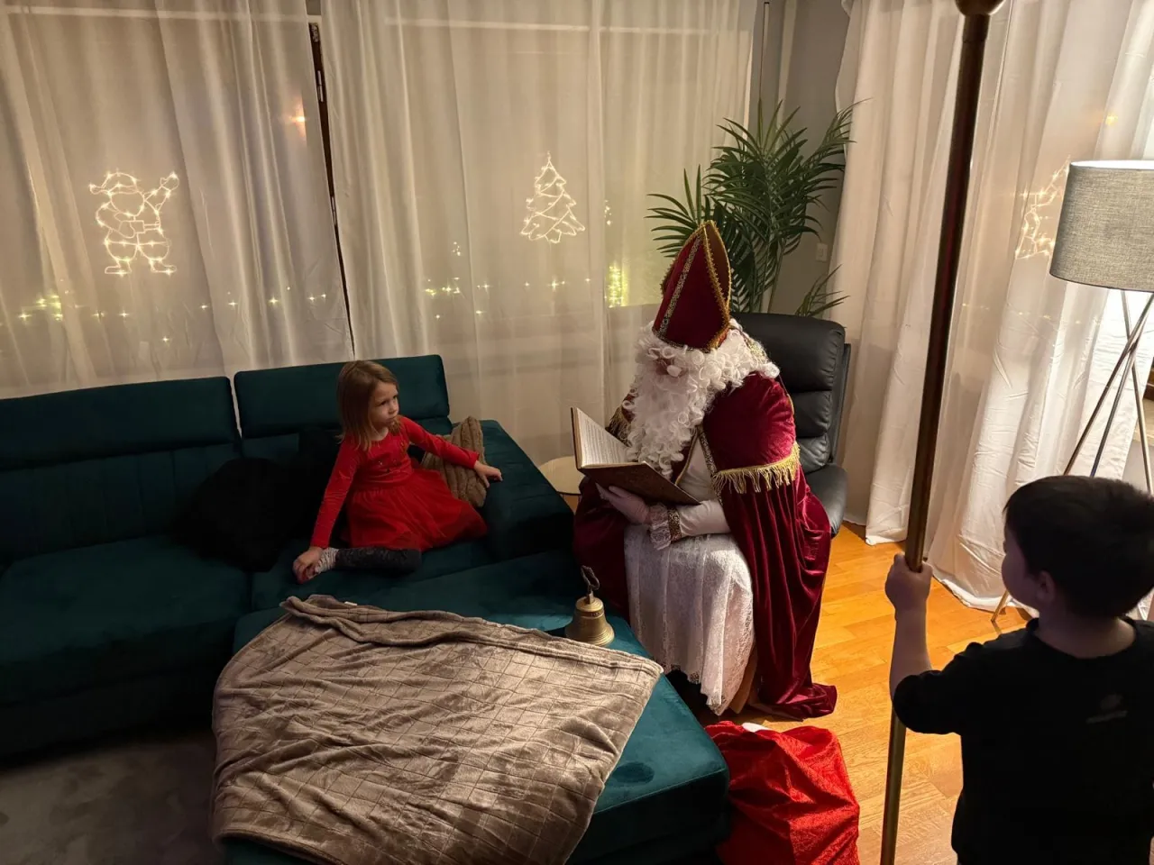 Der Nikolaus unterhält sich mit einem kleinen Mädchen auf der Couch.