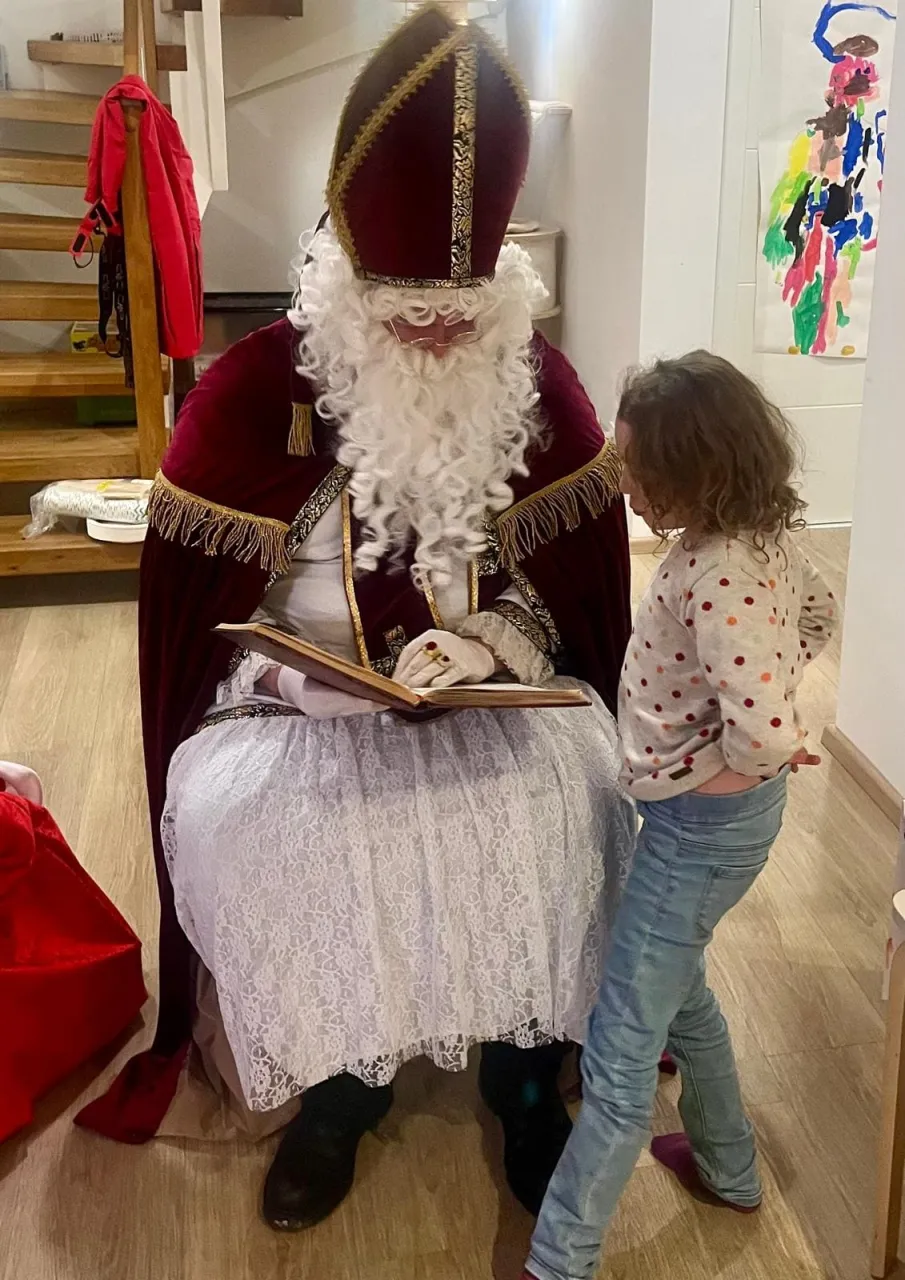 Mädchen schaut gespannt in das goldene Buch, aus diesem der Nikolaus gerade Vorträgt.