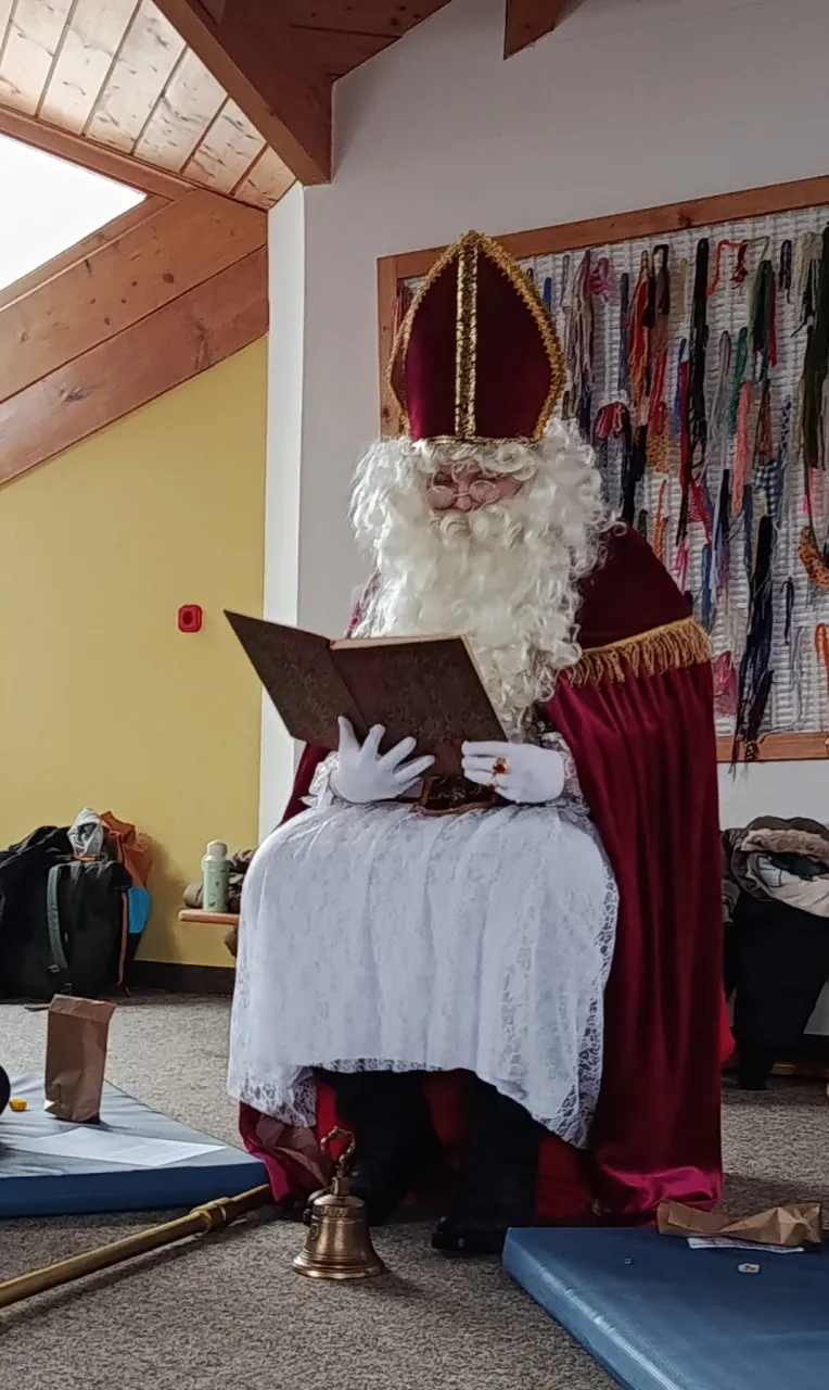 Nikolaus am sitzen und aus dem goldenen Buch vorlesen.