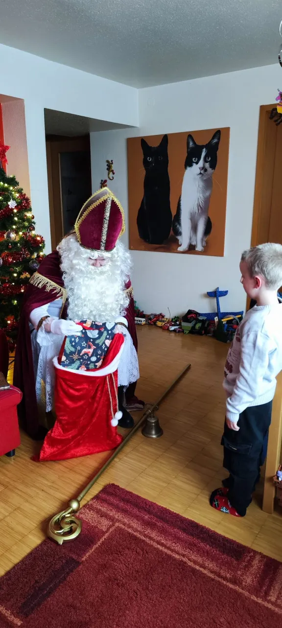 Nikolaus holt ein Geschenk aus seinem Sack für einen Jungen.