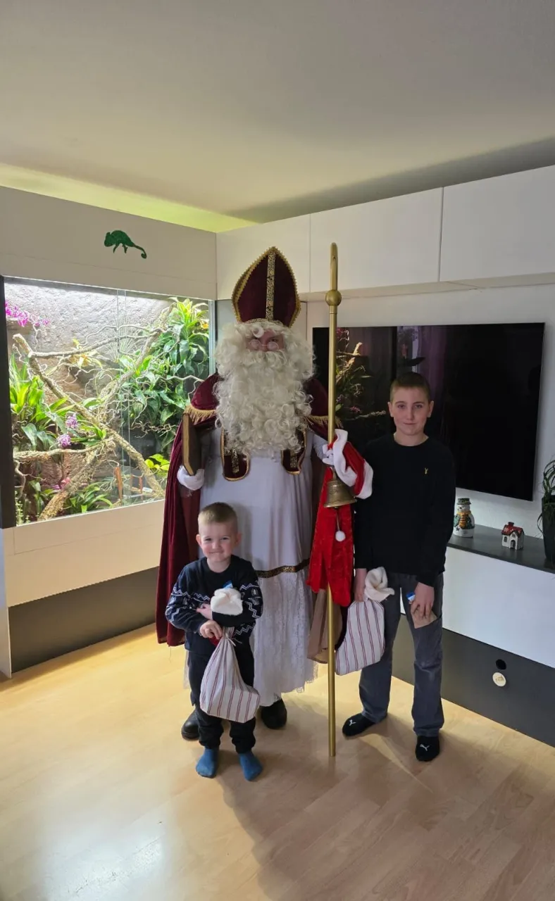 Nikolaus mit zwei Buben die gerade ihre Geschenke bekommen haben.