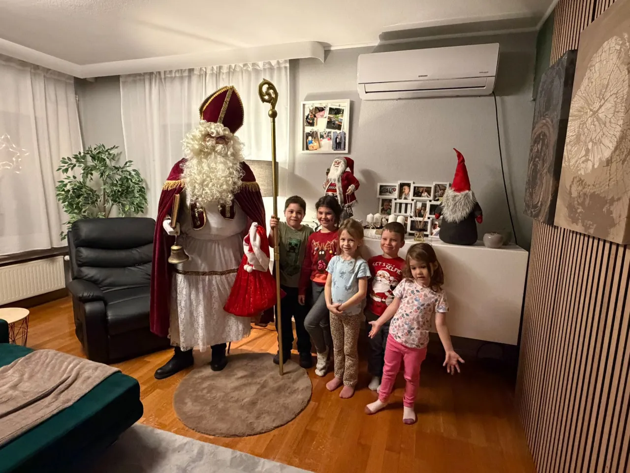 Nikolaus posiert mit einer Gruppe von Kindern im Wohnzimmer.