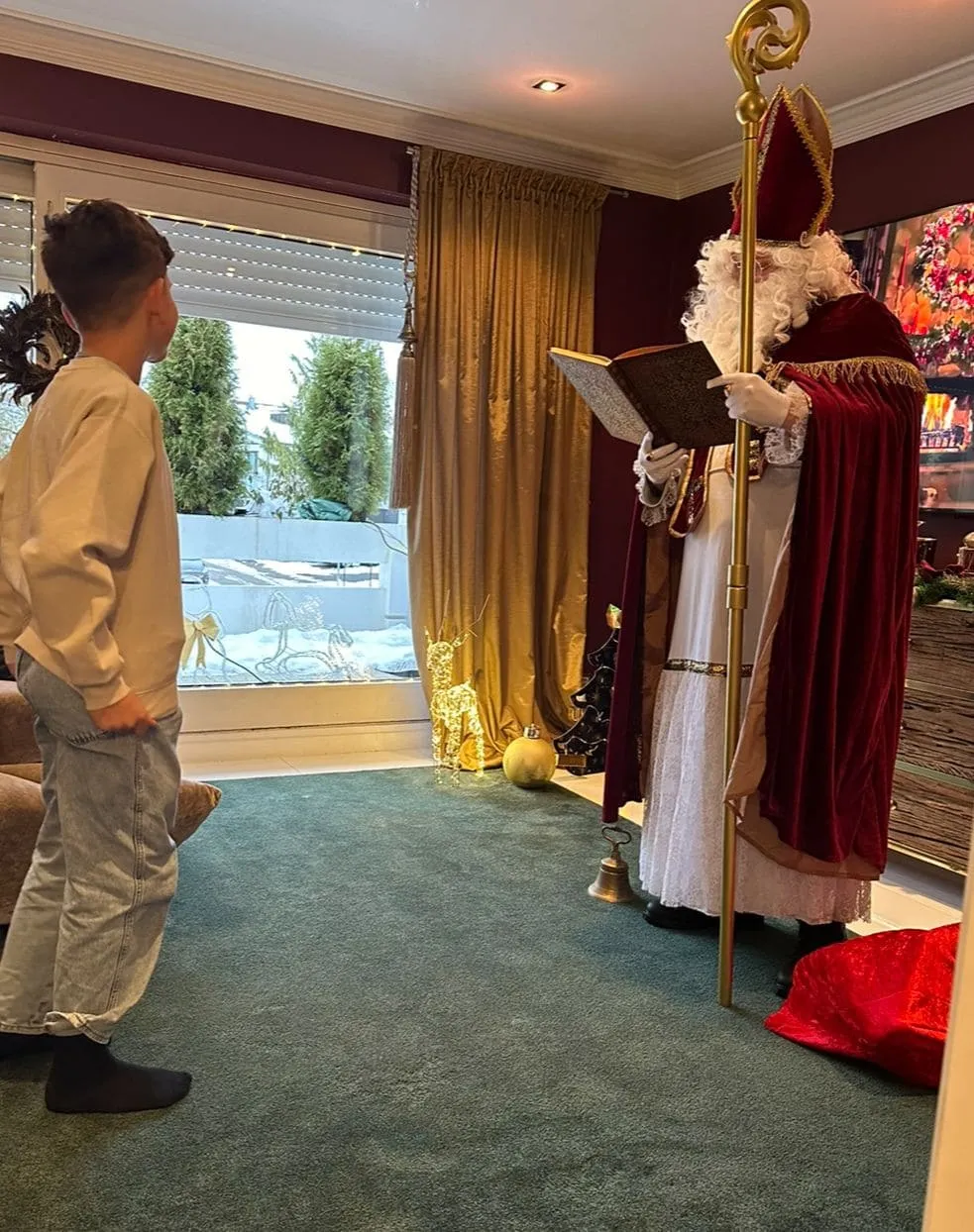 Nikolaus trägt aus dem goldenen Buch vor, vor ihm stehen zwei Kinder.