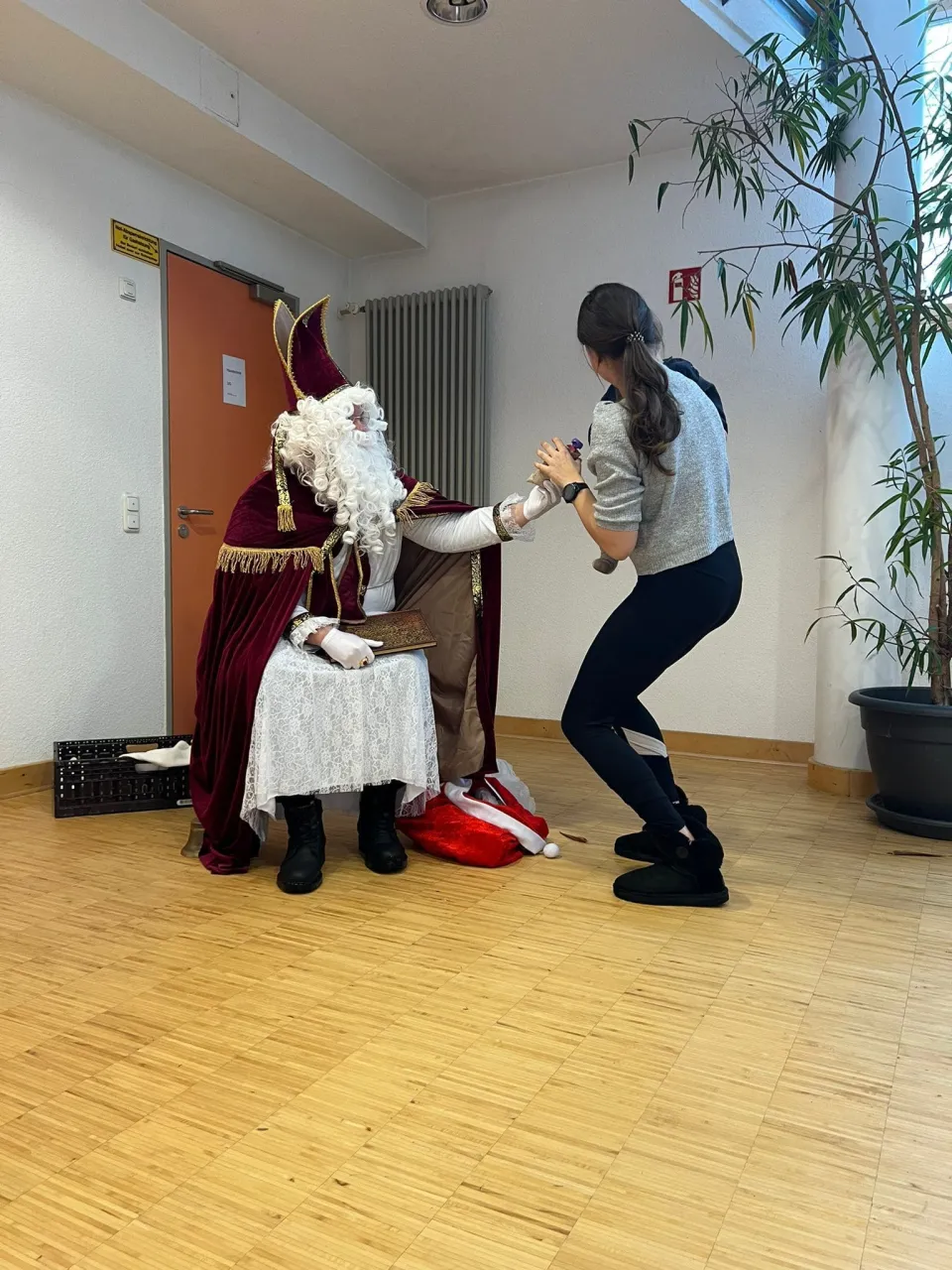 Nikolaus überreicht einem Krippenkind und seiner Mutter ein Geschenk in einer Kita.