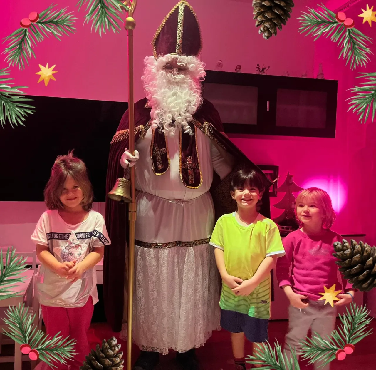 Nikolaus und drei Kinder die lächelnd neben ihm stehen.