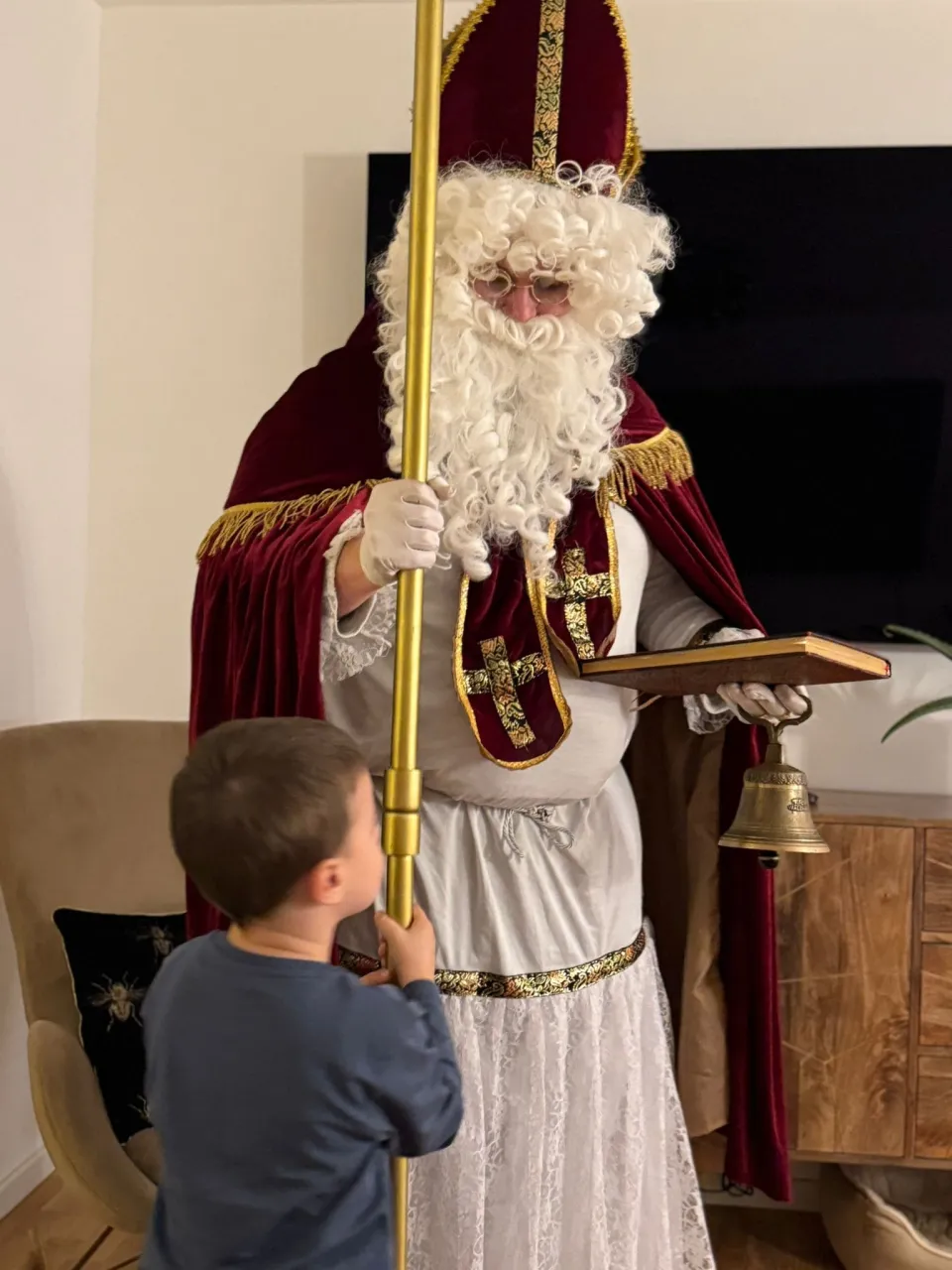Nikolaus und ein kleiner Junge der ihm hilft seinen Stab zu halten.
