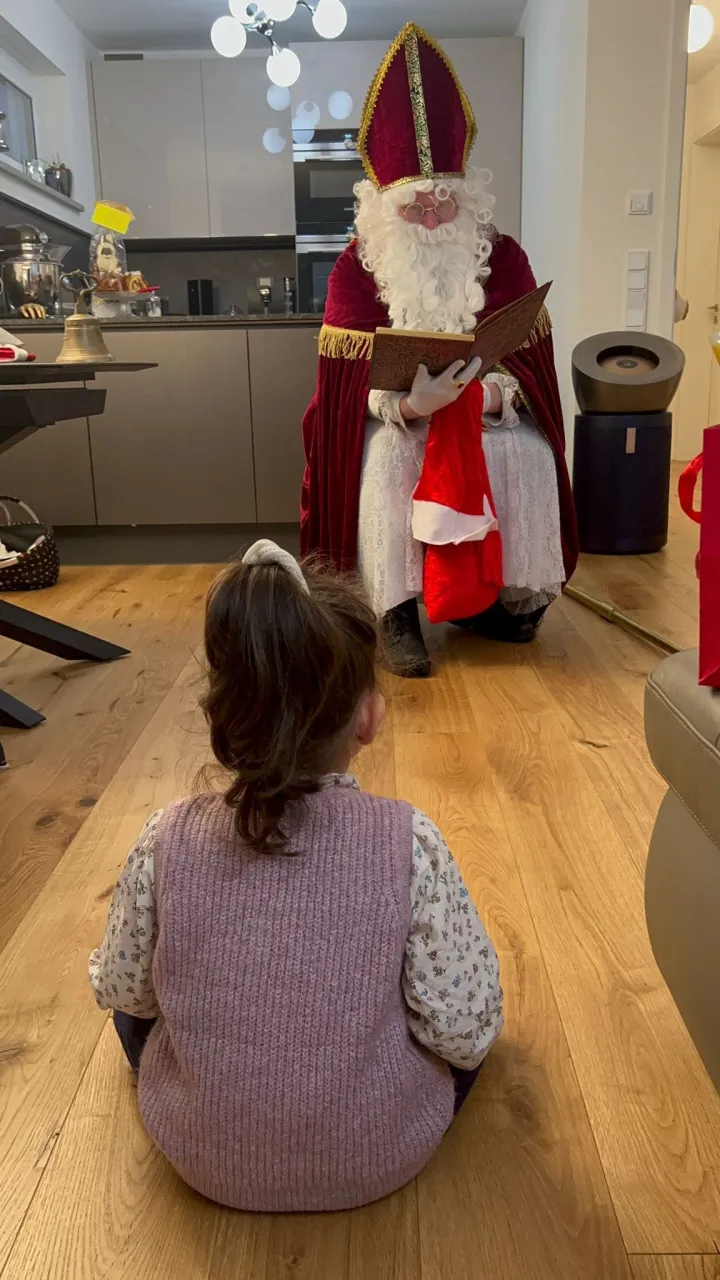 Ein kleines Mädchen sitzt vor dem Nikolaus und lauscht gespannt seinen Worten.