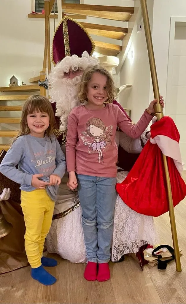 Zwei Kinder halten den Bischofsstab fest während sie lächelnd mit dem Nikolaus ein Foto machen.