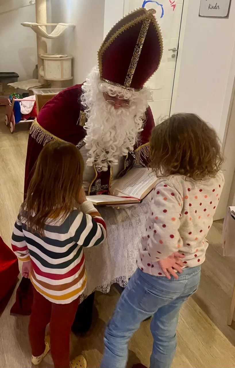 Zwei Kinder lesen zusammen mit dem Nikolaus im goldenen Buch.