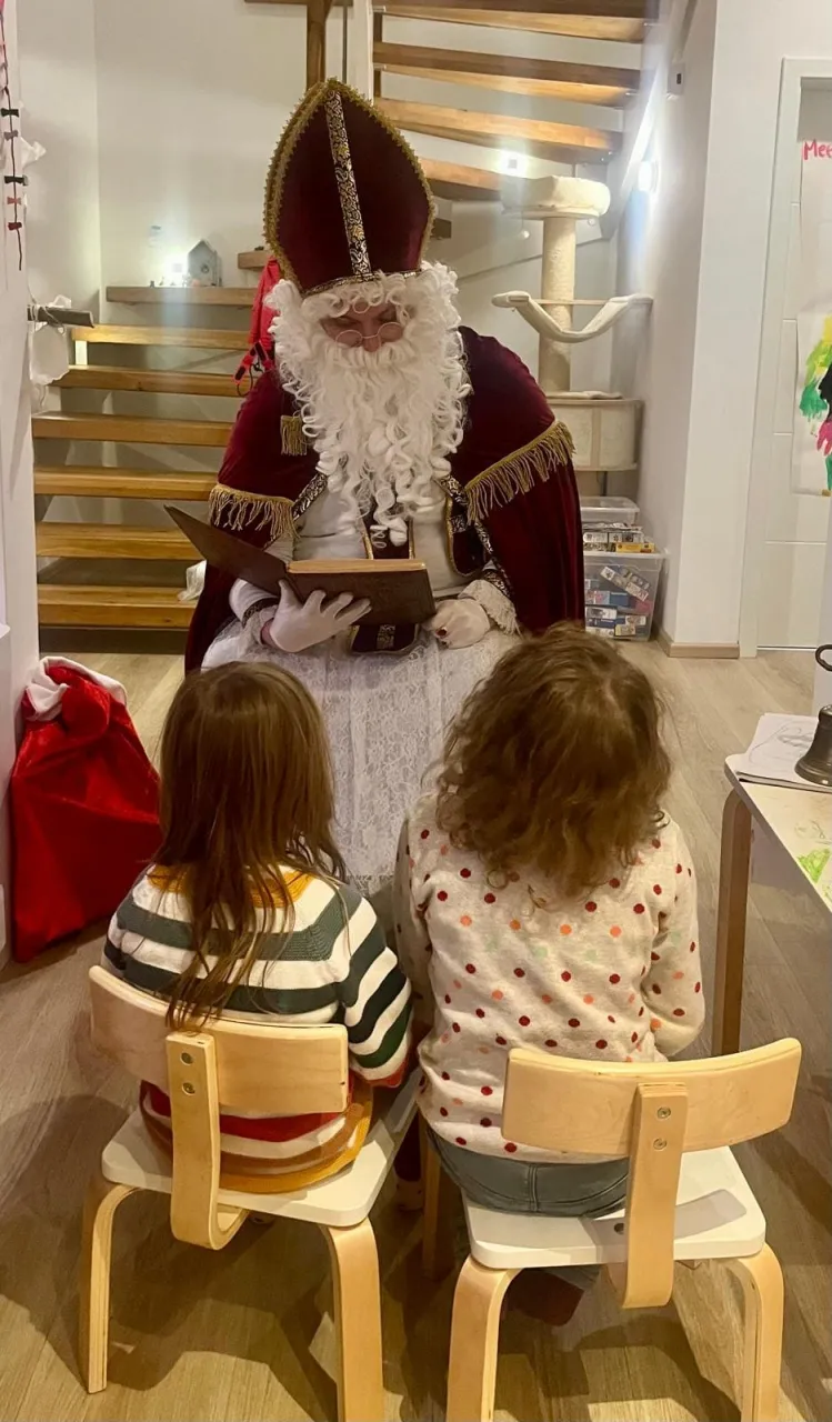 Zwei Kinder sitzen vor dem Nikolaus während dieser aus dem goldenen Buch vorträgt.
