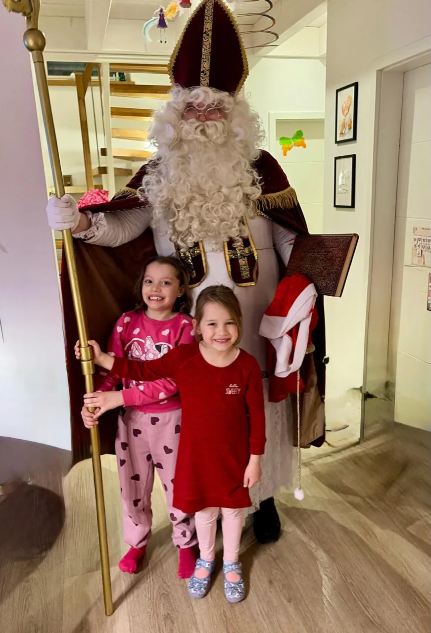 Zwei Mädels halten den Bischofsstab fest während sie lächelnd mit dem Nikolaus ein Foto machen.