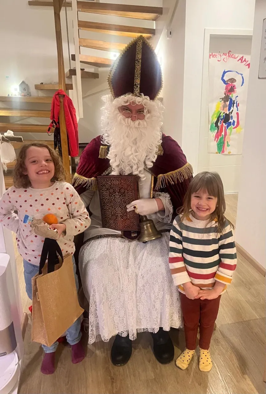 Zwei strahlende Mädchen mit Geschenken posieren für ein Foto mit dem Nikolaus.