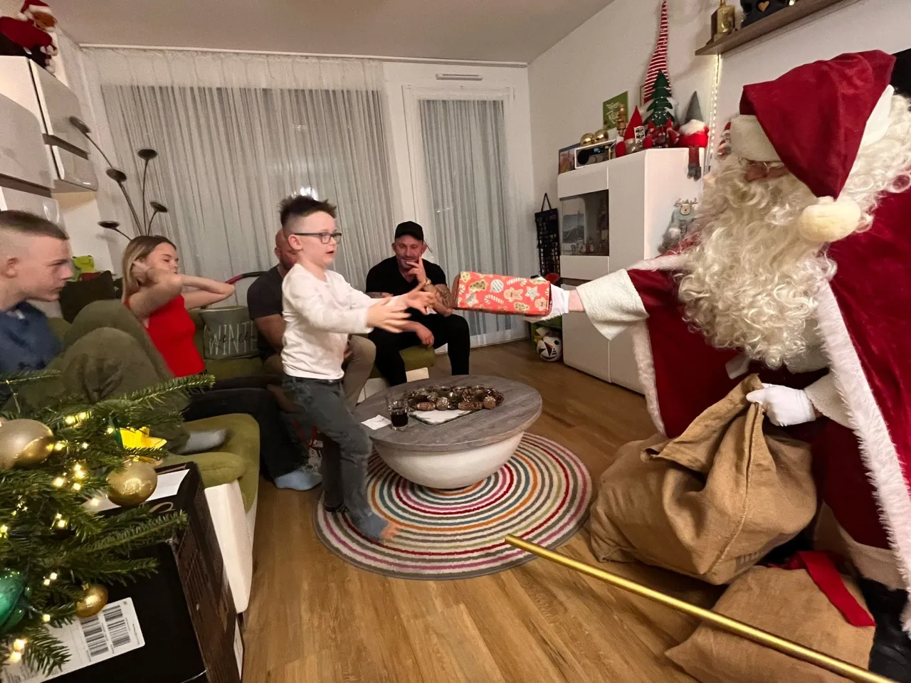 Der Weihnachtsmann überreicht einem Kind sein Geschenk.