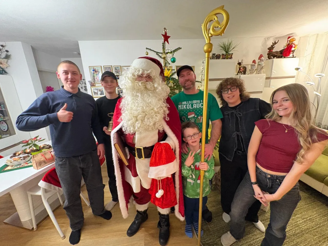 Gruppenfoto vom Weihnachtsmann mit einer Familie mit fünf Jugendlichen und einem Papa, der Kleinste hält den Stab vom Weihnachtsmann.