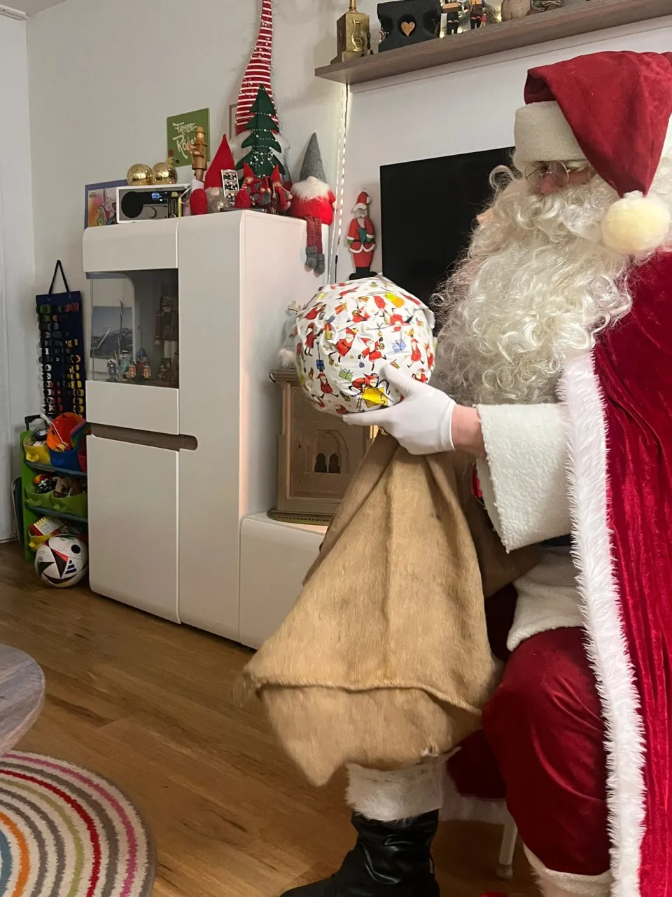 Weihnachtsmann hält ein verpacktes Geschenk in den Händen.