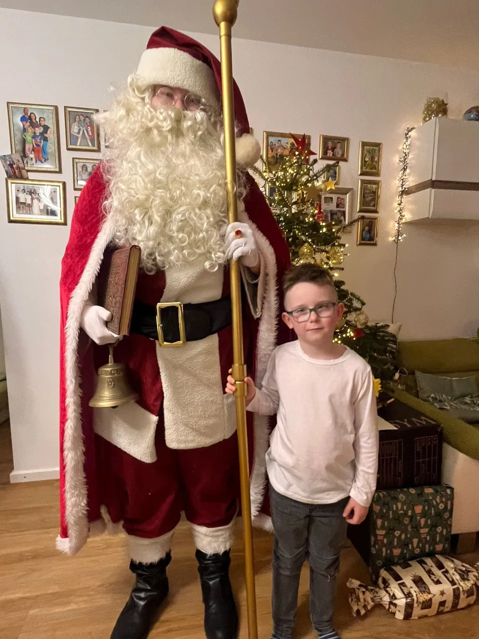 Weihnachtsmann und ein kleiner Junge, der Junge hilft dem Weihnachtsmann den Stab zu halten.