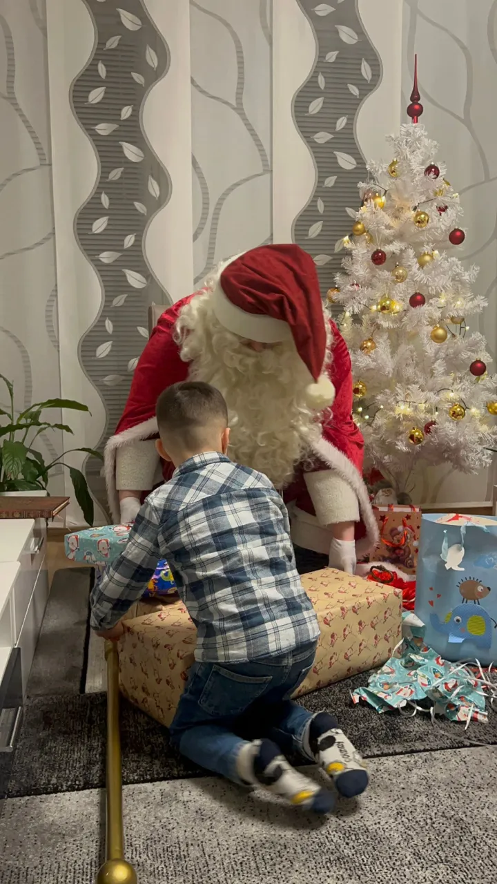 Weihnachtsmann und kleiner Junge sehen sich die Geschenke an.