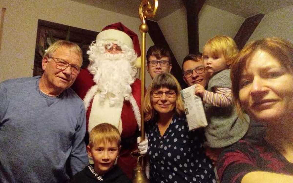 Weihnachtsmann steht mit einer mehrköpfigen Familie beim Fest zusammen
