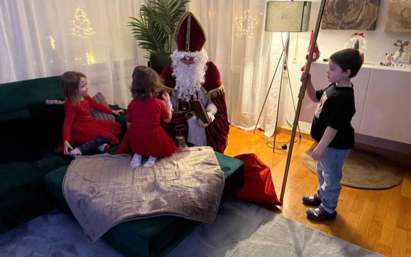 Ein Junge hält den Bischofsstab, während der Nikolaus mit zwei Mädchen spricht