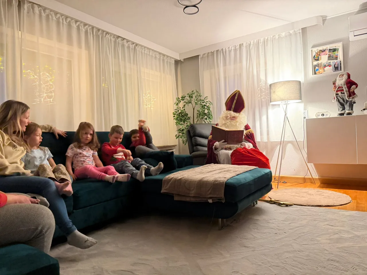 Kinder auf der couch und der Nikolaus am vortragen aus dem goldenen Buch.