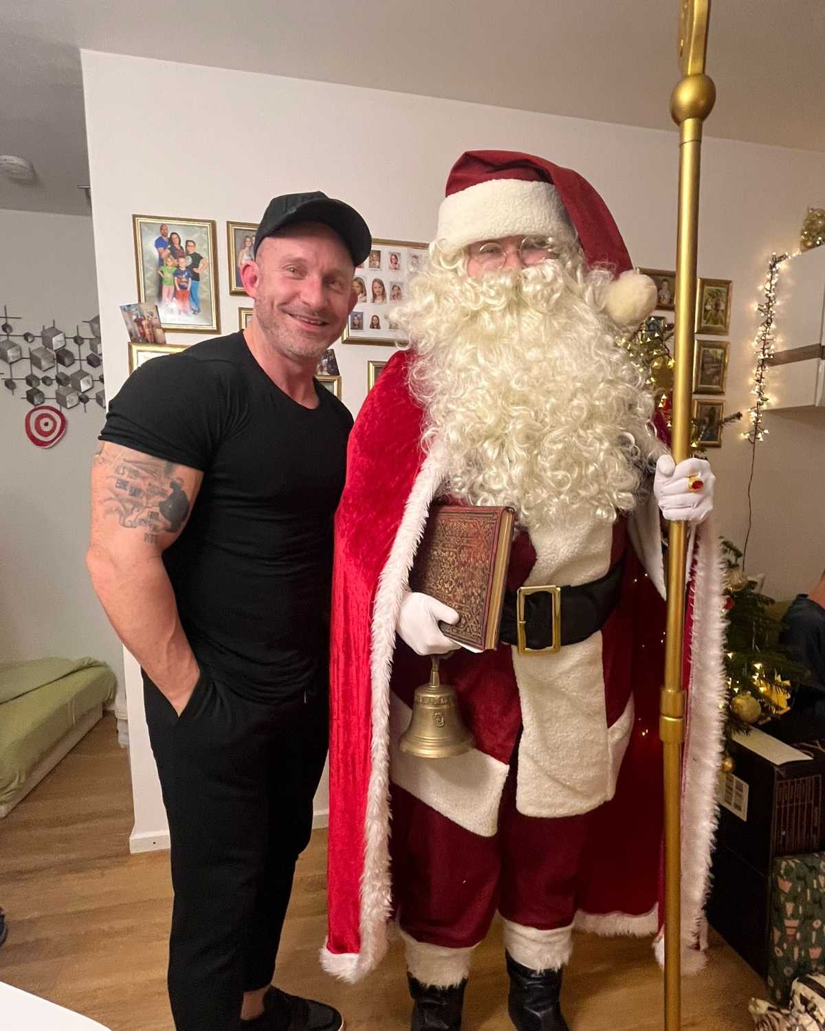 Weihnachtsmann bei einem persönlichen Moment nach dem Auftritt Weihnachtsmann steht neben einem lächelnden Mann