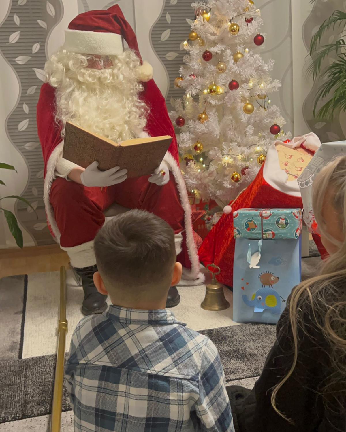 Weihnachtsmann beim Vorlesen aus dem goldenen Buch Weihnachtsmann trägt aus dem goldenen Buch vor, während ein Junge zuhört