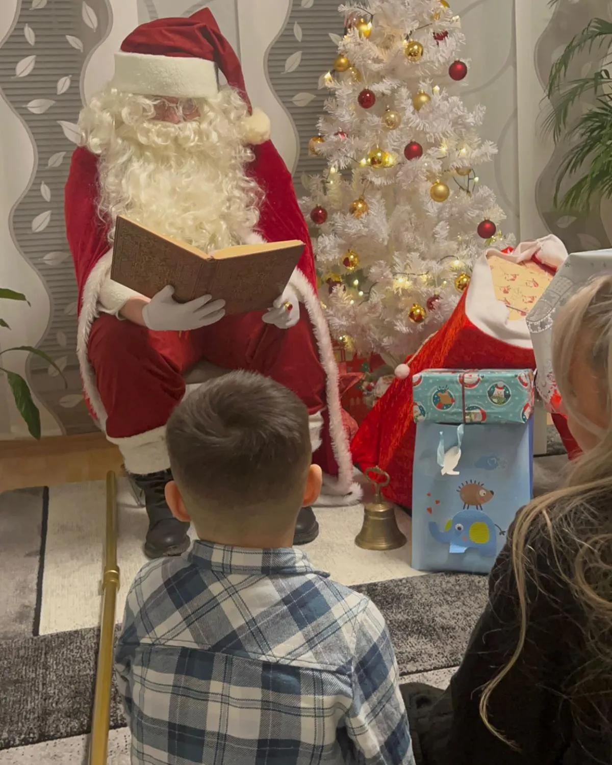 Weihnachtsmann trägt aus dem goldenen Buch vor, während ein Junge zuhört