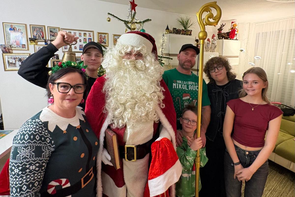Weihnachtsmann bei einem persönlichen Familienbesuch Weihnachtsmann mit einer Familie aus Eltern, Geschwistern und Söhnen, der Kleinste hält seinen Stab