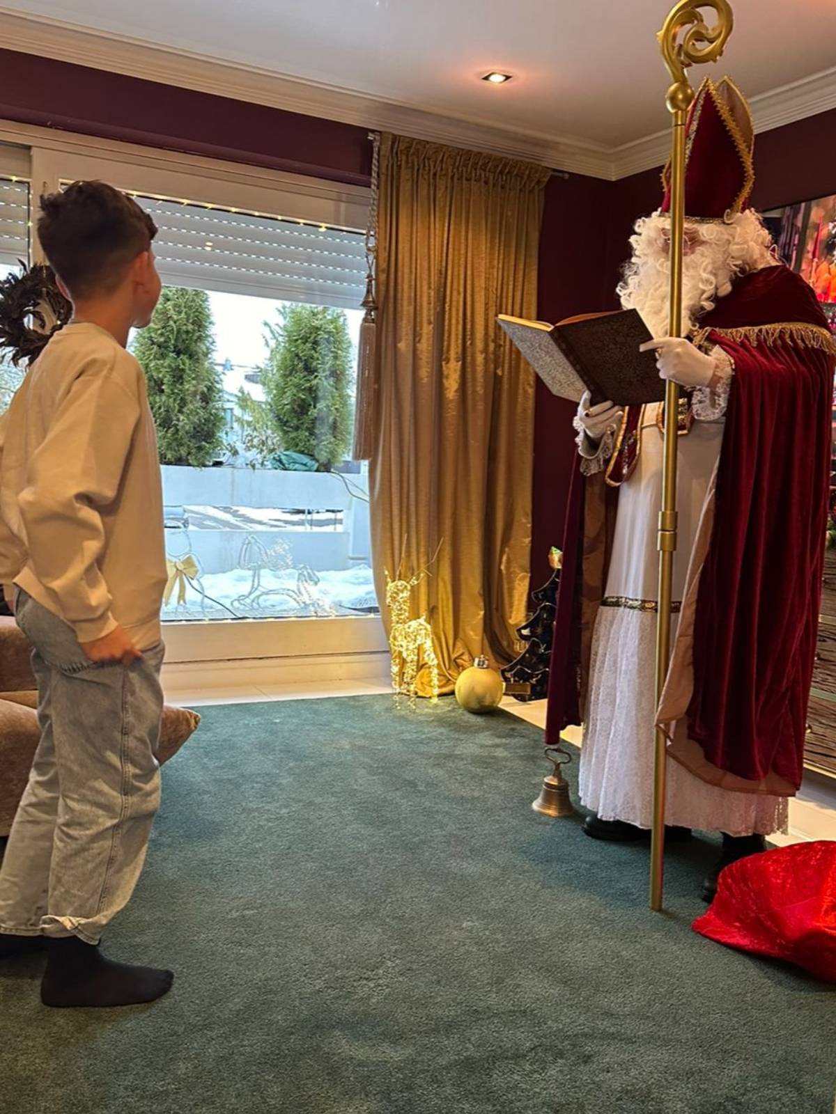 Nikolaus beim Vorlesen aus dem goldenen Buch Nikolaus trägt aus dem goldenen Buch vor, vor ihm stehen zwei Kinder