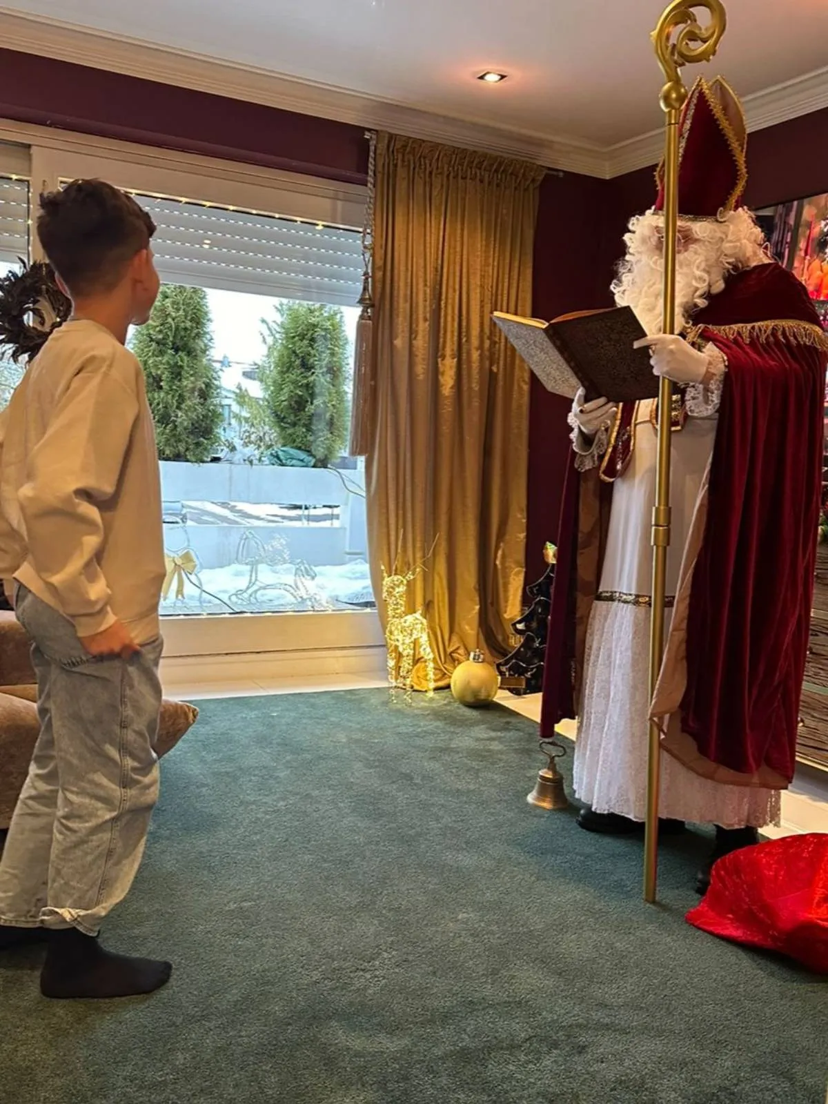 Nikolaus beim Vorlesen aus dem goldenen Buch Nikolaus trägt aus dem goldenen Buch vor, vor ihm stehen zwei Kinder