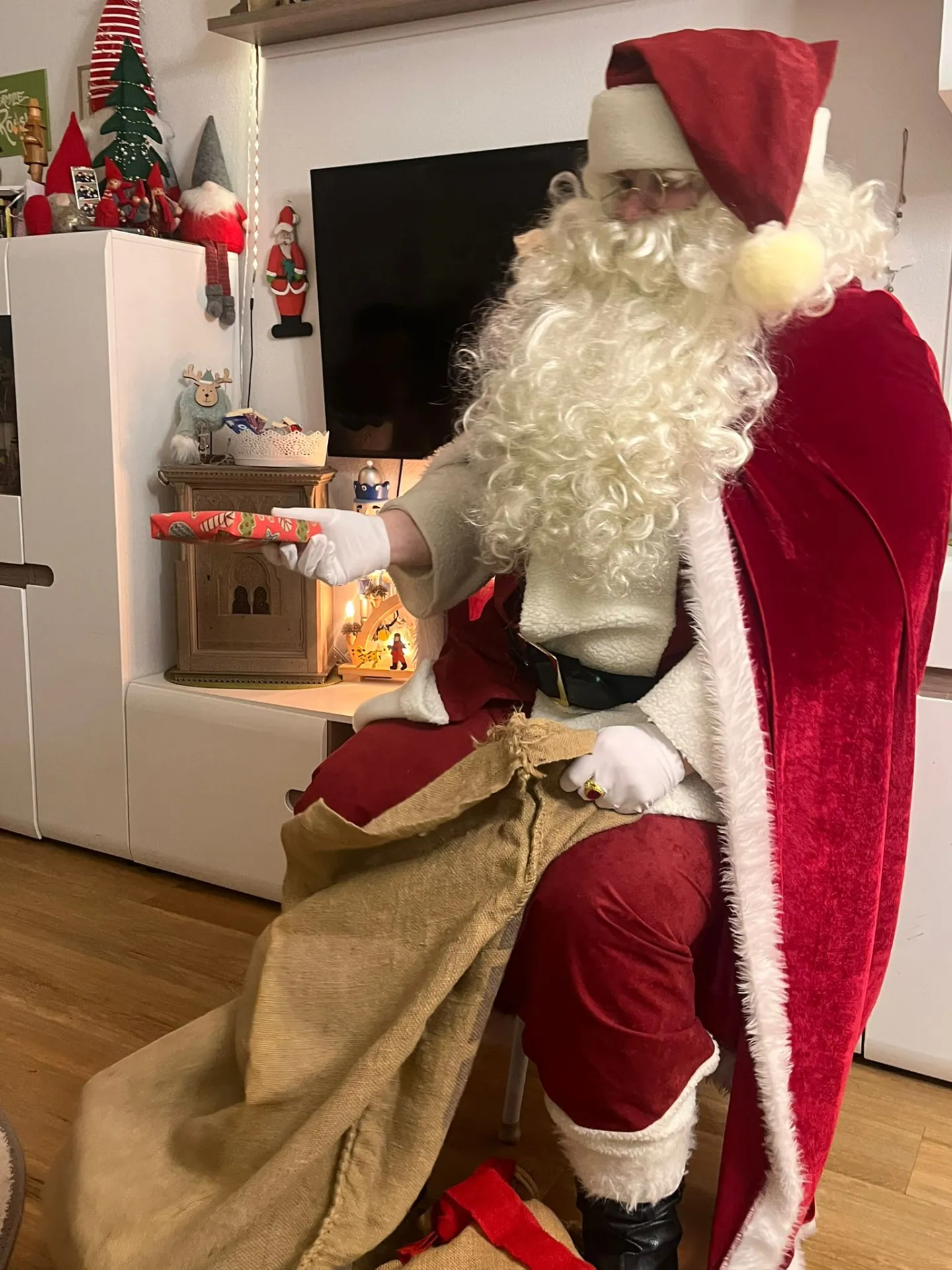 Weihnachtsmann überreicht einem Kind sein Geschenk
