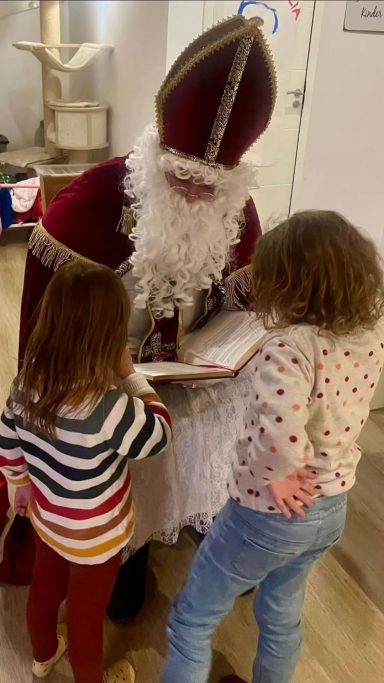 Nikolaus in Augsburg liest Kindern aus dem goldenen Buch bei einer Familienfeier vor